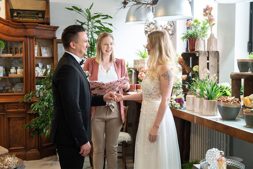 A bride and groom are getting married in a flower shop.