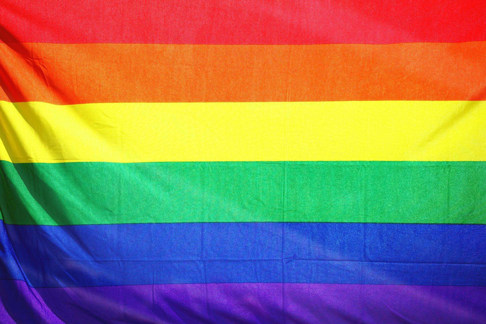 Rainbow flag with horizontal stripes in red, orange, yellow, green, blue, and purple.