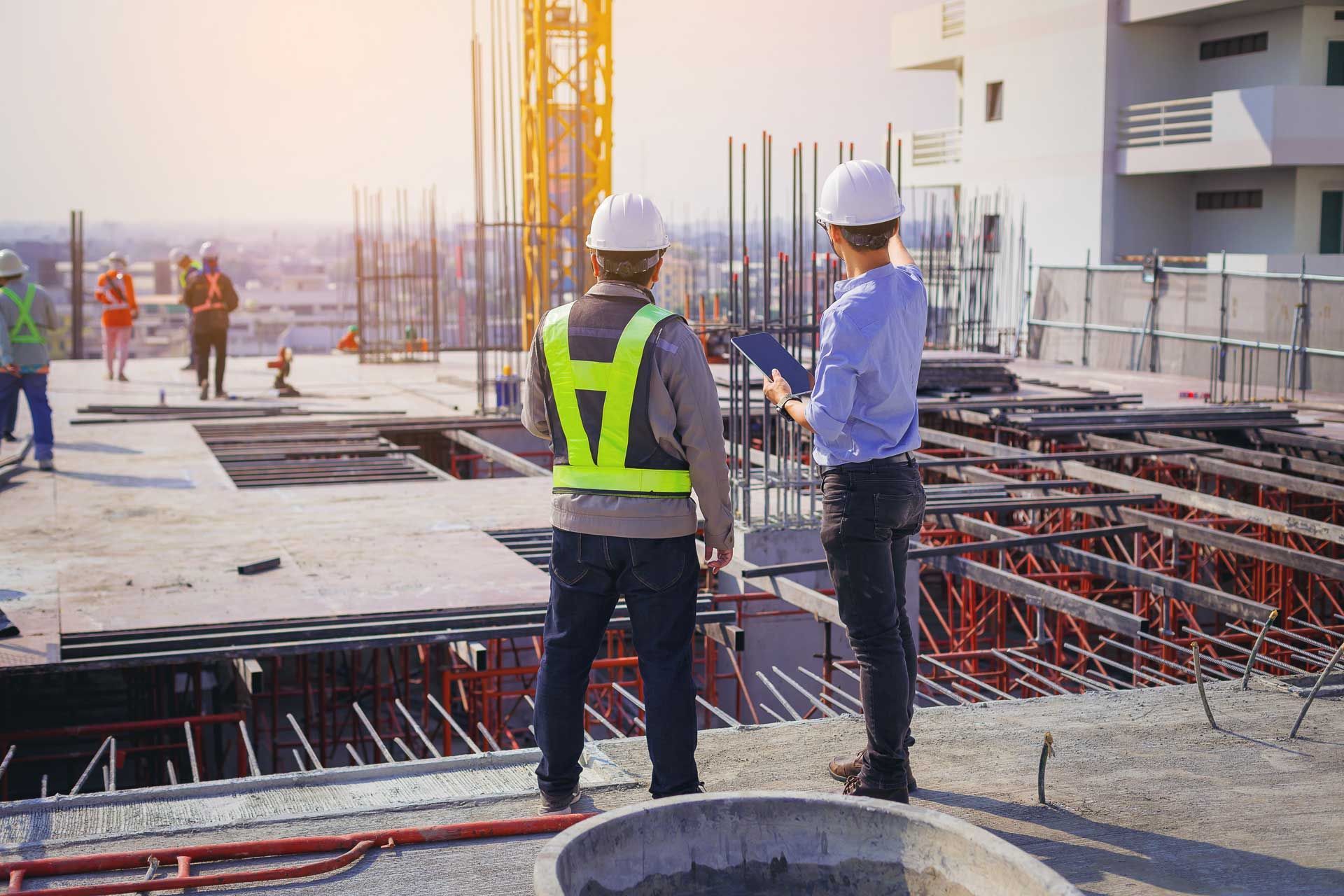 Construction workers on a building site, reviewing blueprints in bright sunlight.