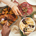 Overhead view of a group of people sitting around a festive dinner table filled with various dishes and drinks.