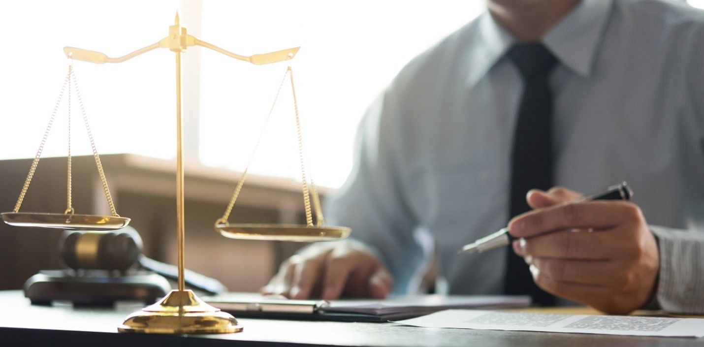 A Man Is Sitting At A Desk With A Scale Of Justice In The Background — Memphis, TN — Vaccine Injury 