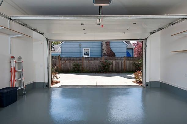 A garage with the door open and a ladder in it.