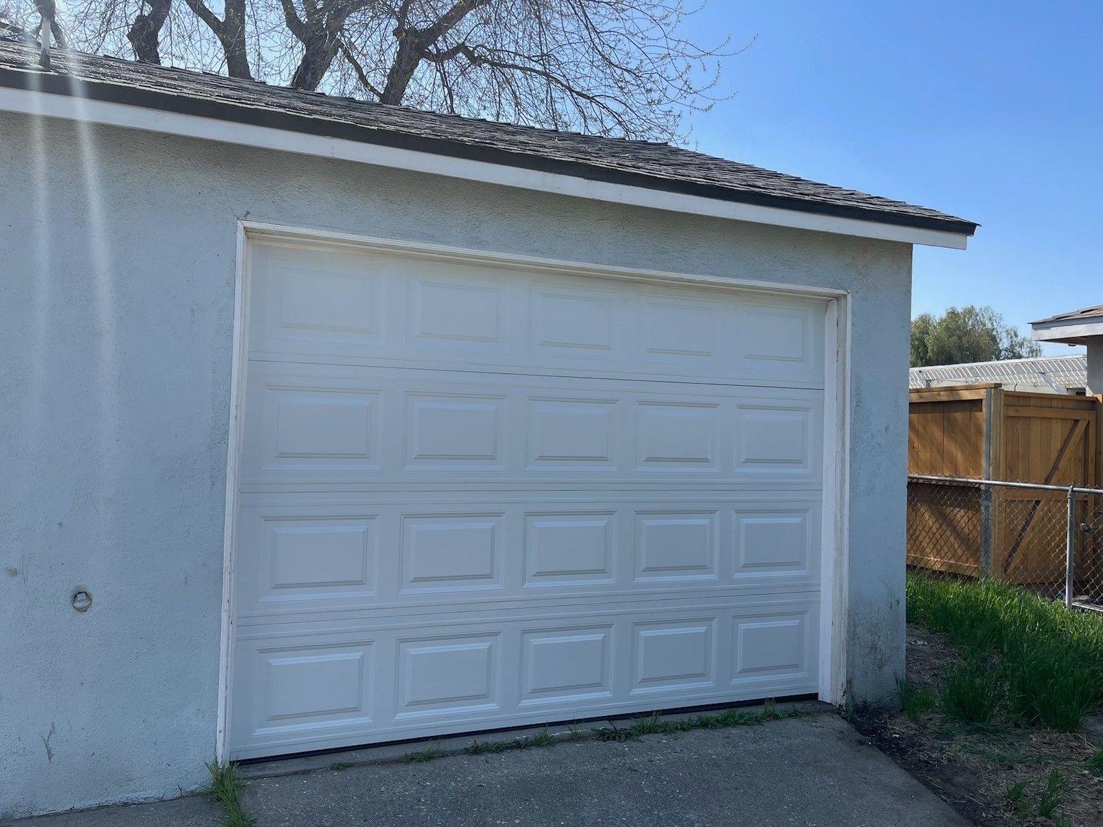 A white garage door is open on a sunny day.