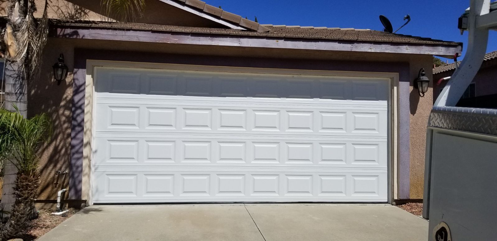 White garage door of a house under a clear, blue sky.