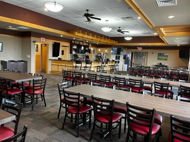 A restaurant with long tables and red chairs