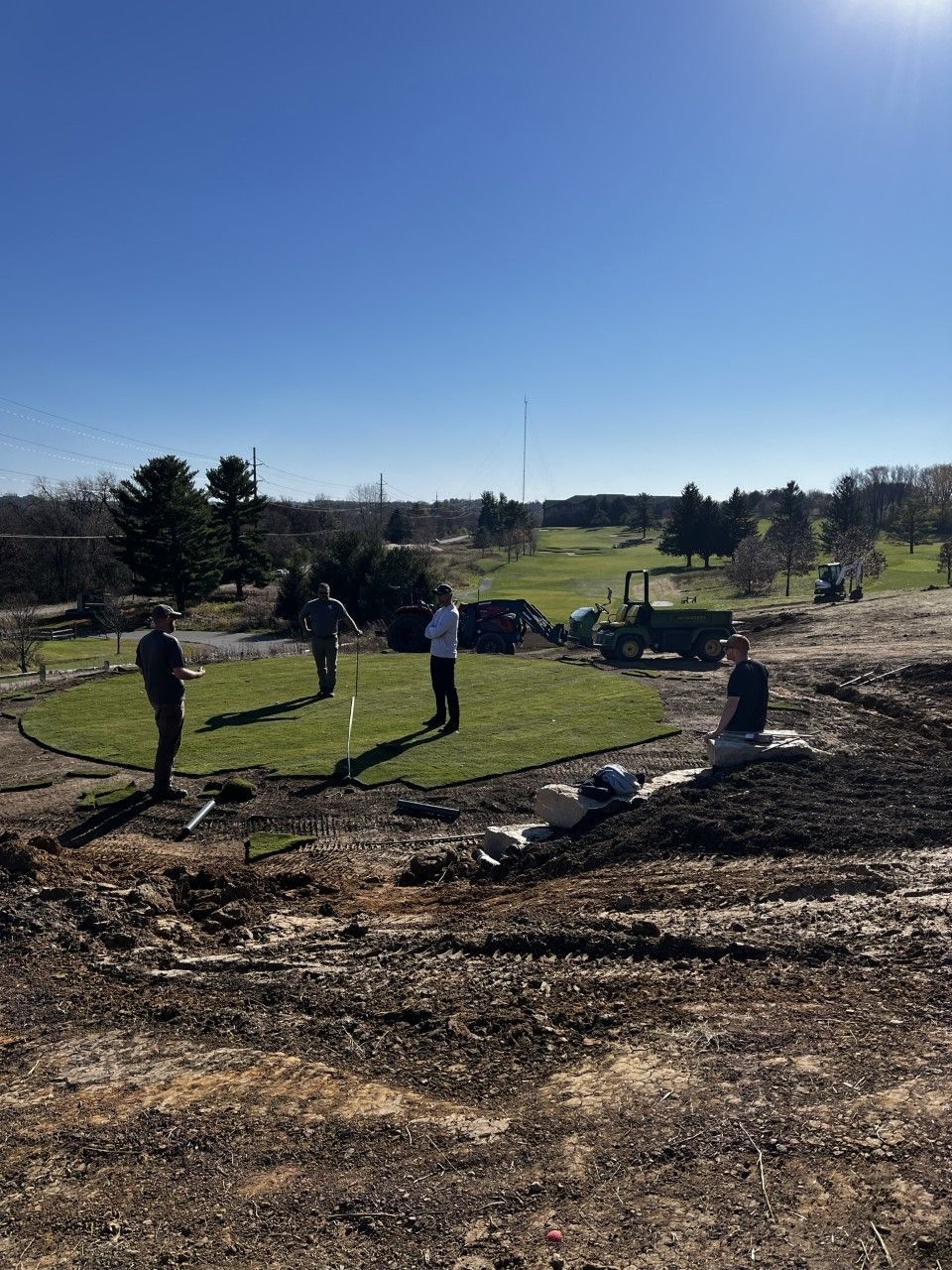 A group of people are standing on top of a dirt field.