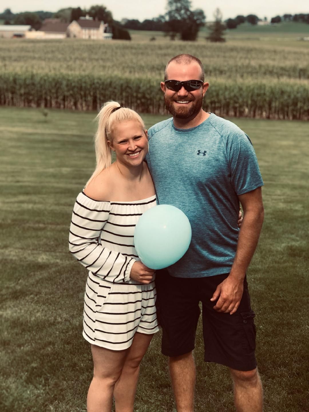 A man and a woman are standing next to each other holding a blue balloon.