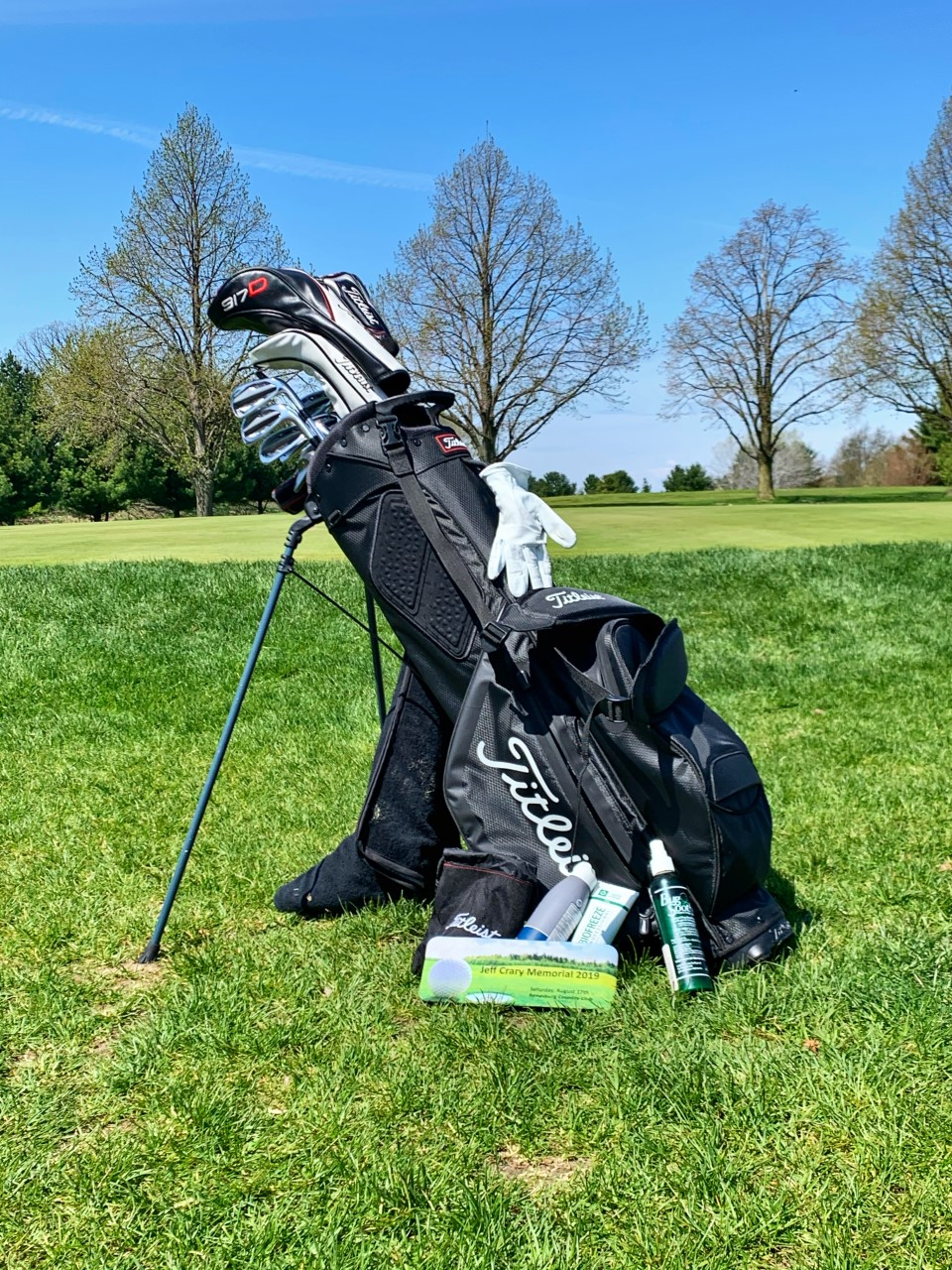 A golf bag is sitting on top of a lush green golf course.