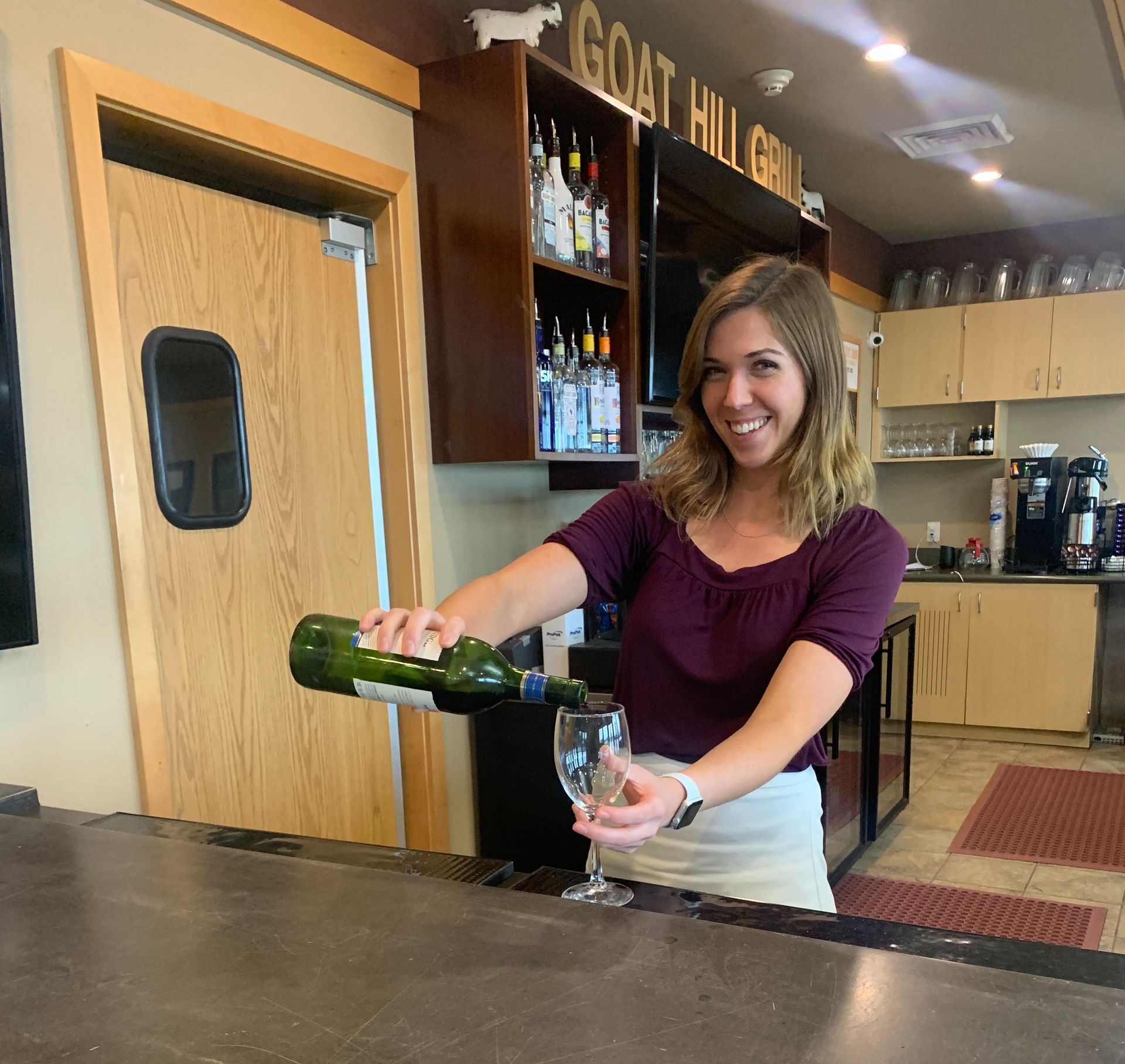 A woman pouring a bottle of wine into a glass