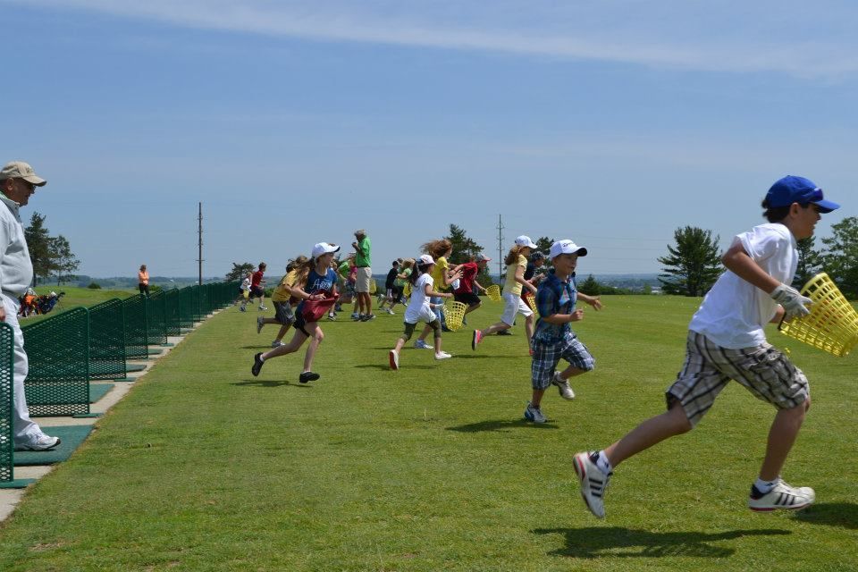 A group of children are running on a grassy field