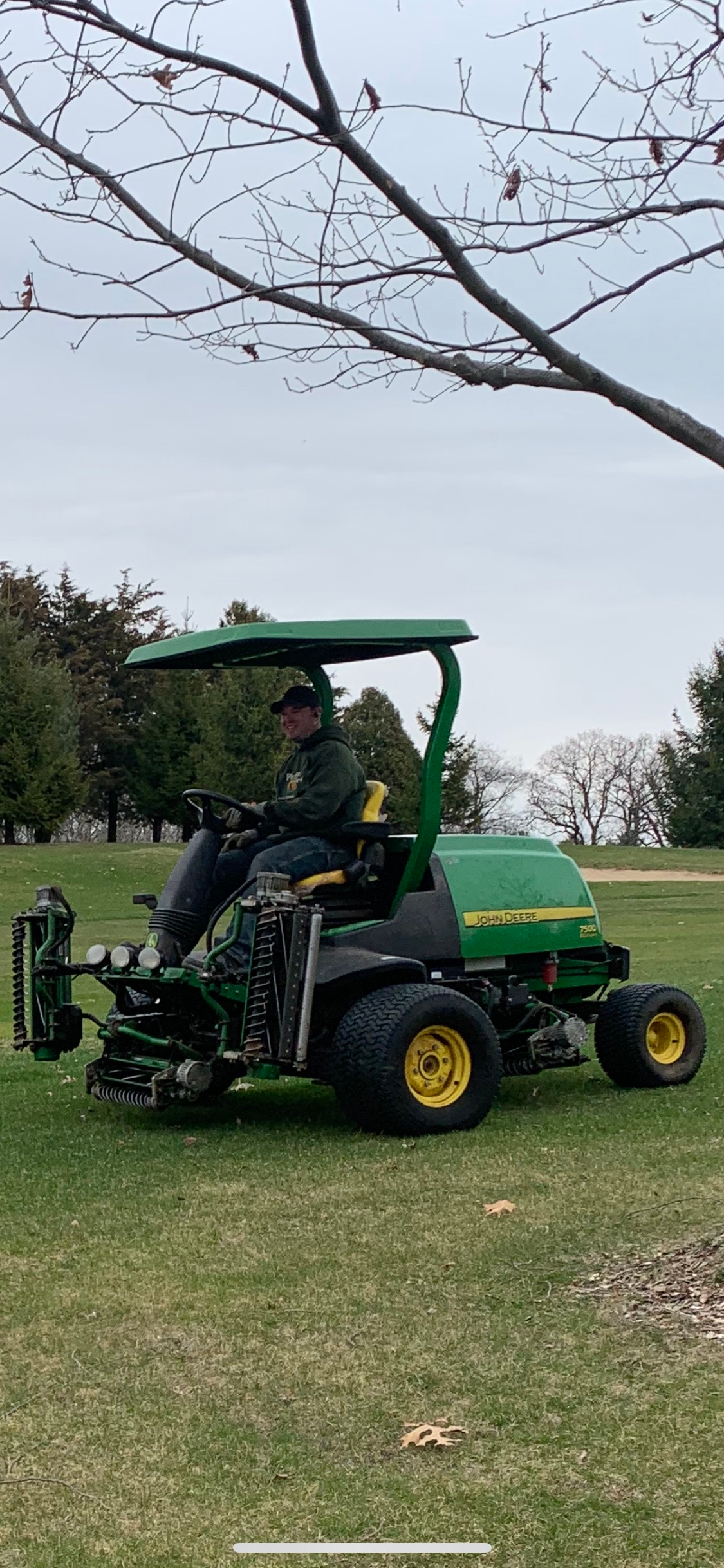 A man is riding a john deere lawn mower on a lush green field.