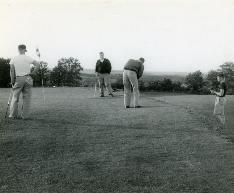 A group of men are playing golf in a black and white photo