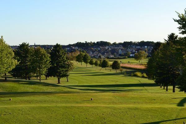 A golf course with trees and a city in the background