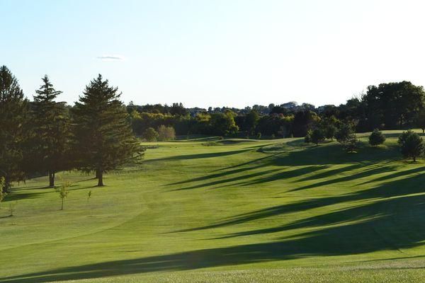 A golf course with trees and a blue sky in the background