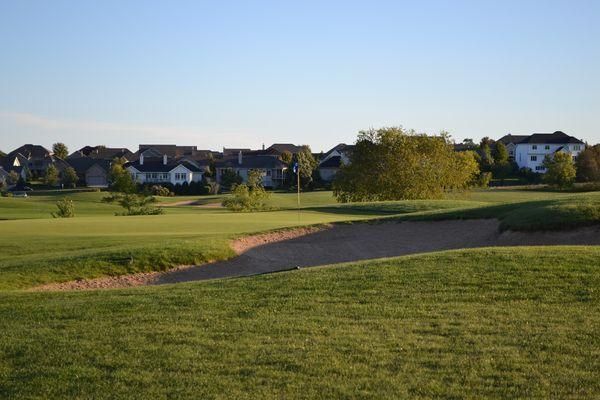 A golf course in a residential area with houses in the background.