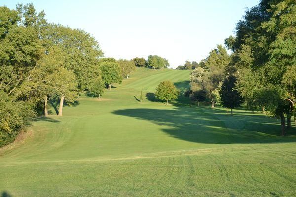 A golf course surrounded by trees and grass on a sunny day