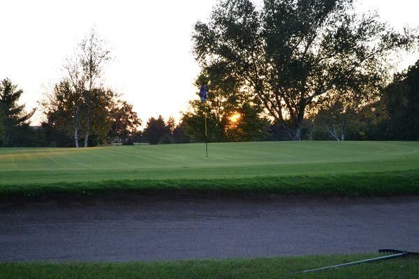 A golf course with a sunset in the background
