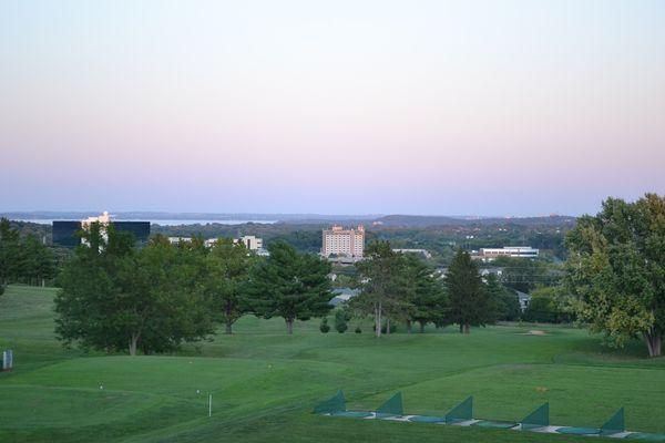 A view of a golf course with trees and buildings in the background