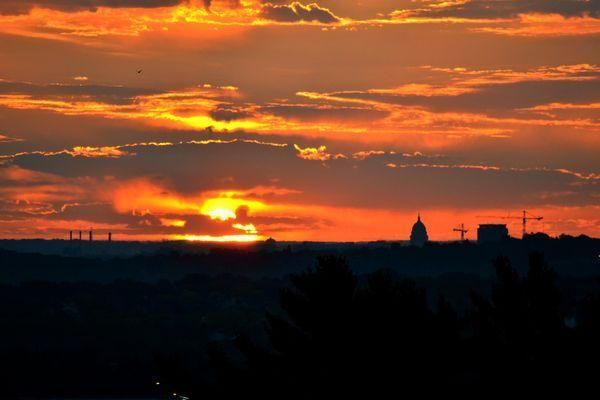 A sunset over a city with a silhouette of a church in the foreground.
