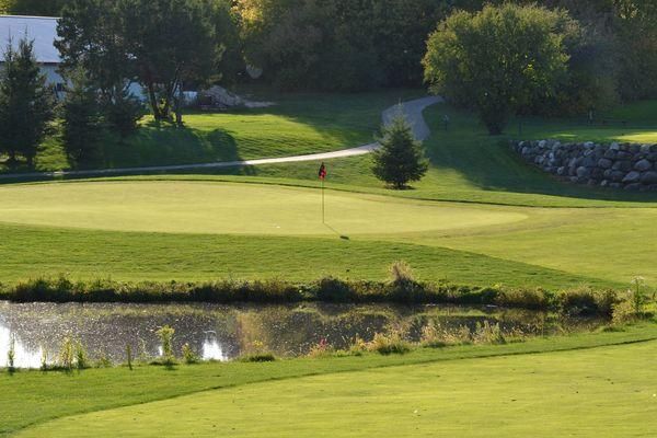 A golf course with a pond in the middle of it.