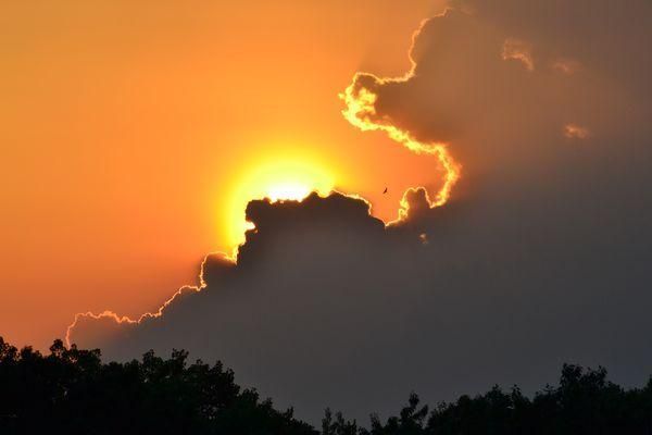 The sun is shining through the clouds at sunset.