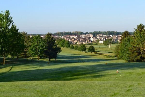A golf course with trees and houses in the background