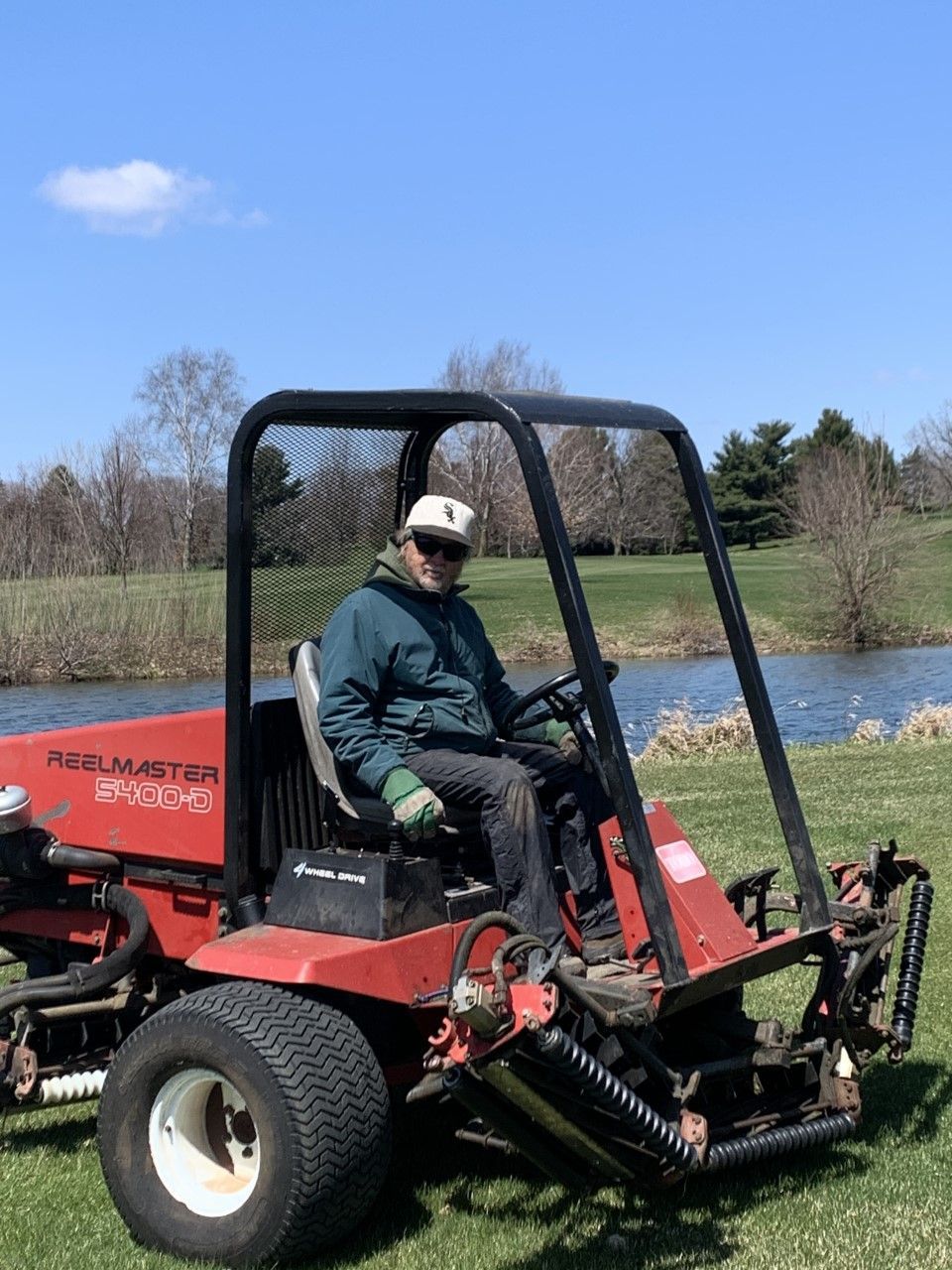 A man is riding a lawn mower on a lush green field.