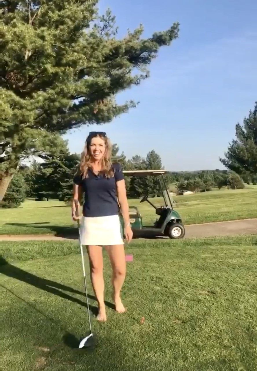 A woman is standing on a golf course holding a golf club