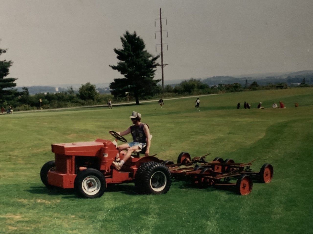 A man is riding a red tractor on a lush green field