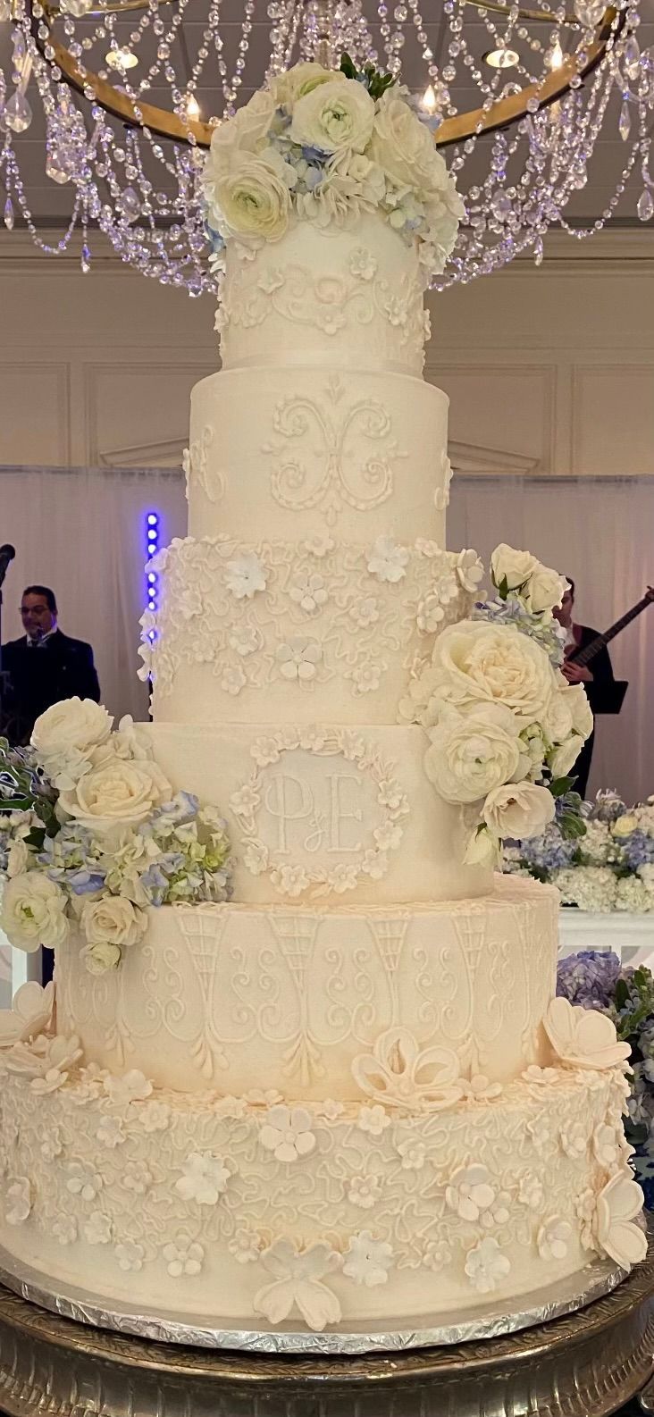 a large white wedding cake is sitting on top of a silver cake stand .