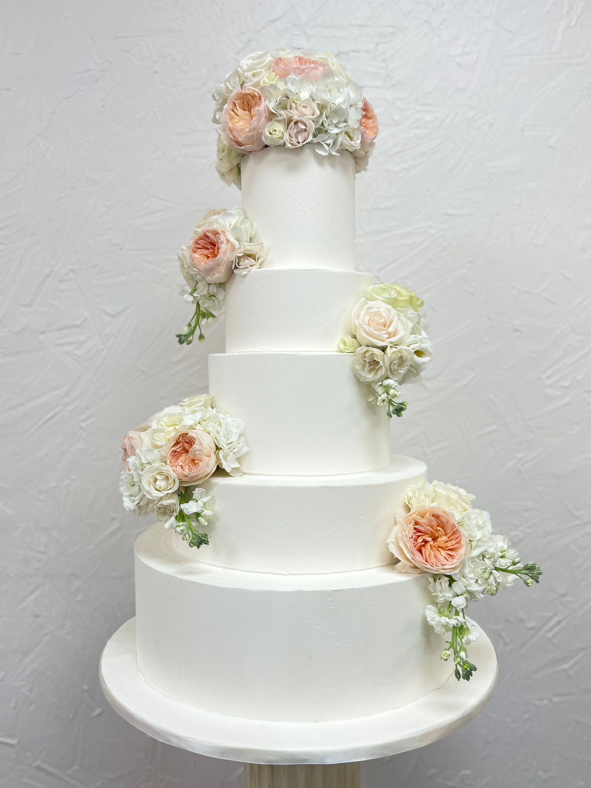 a white wedding cake with flowers on top of it .