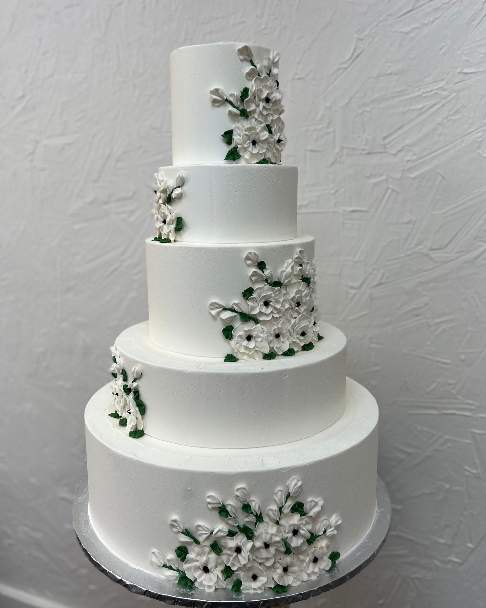 a white wedding cake with green flowers on it