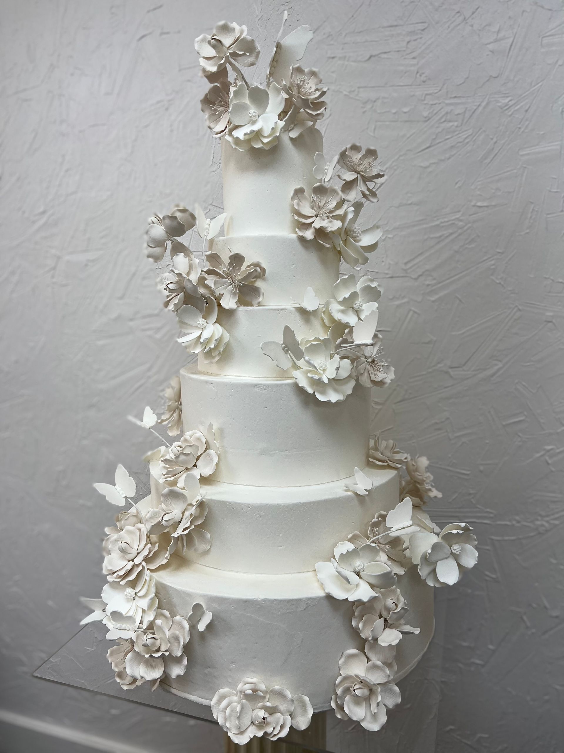 a white wedding cake with white flowers and butterflies on it .