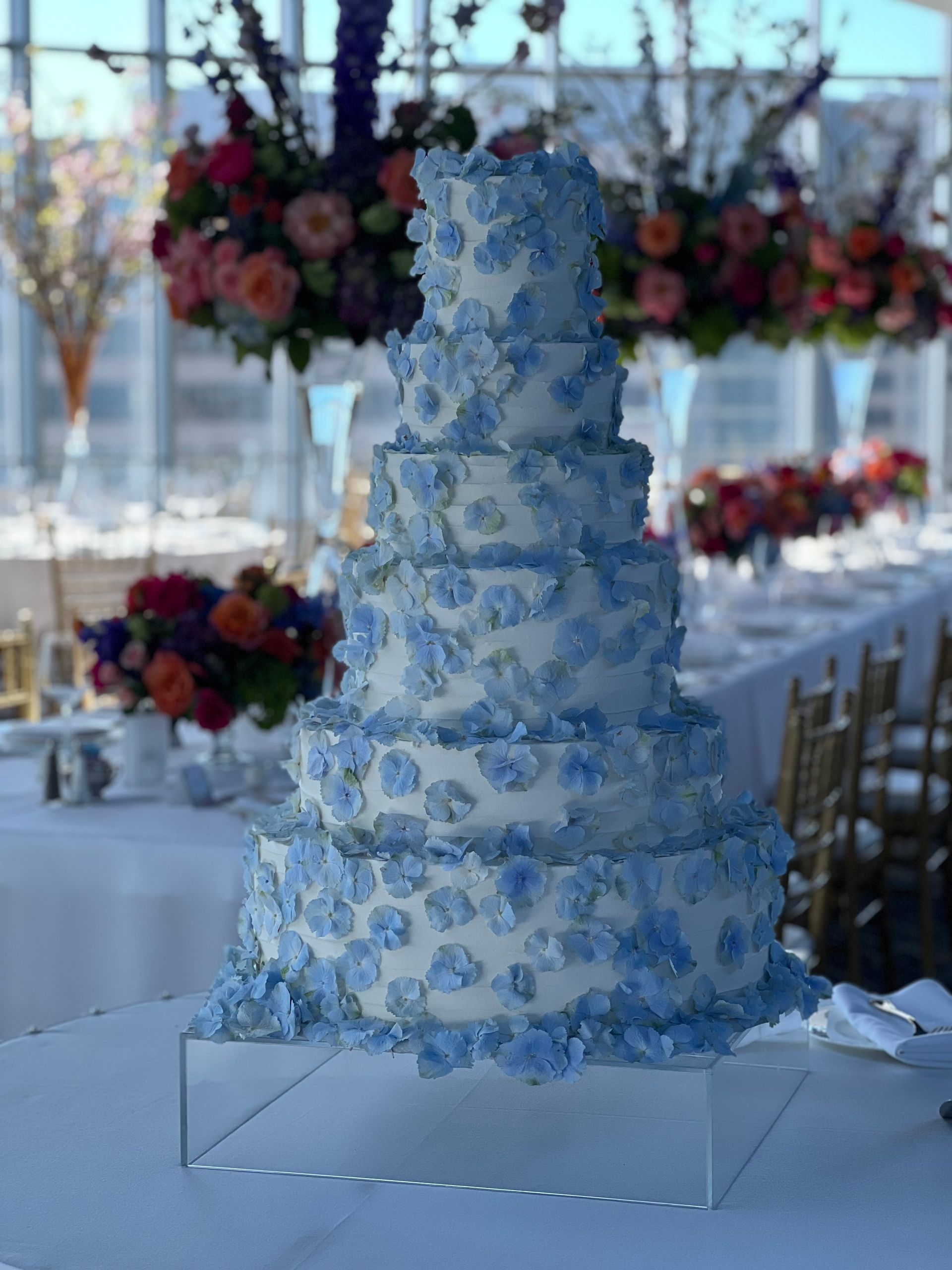 a wedding cake with blue flowers on it is sitting on top of a table .