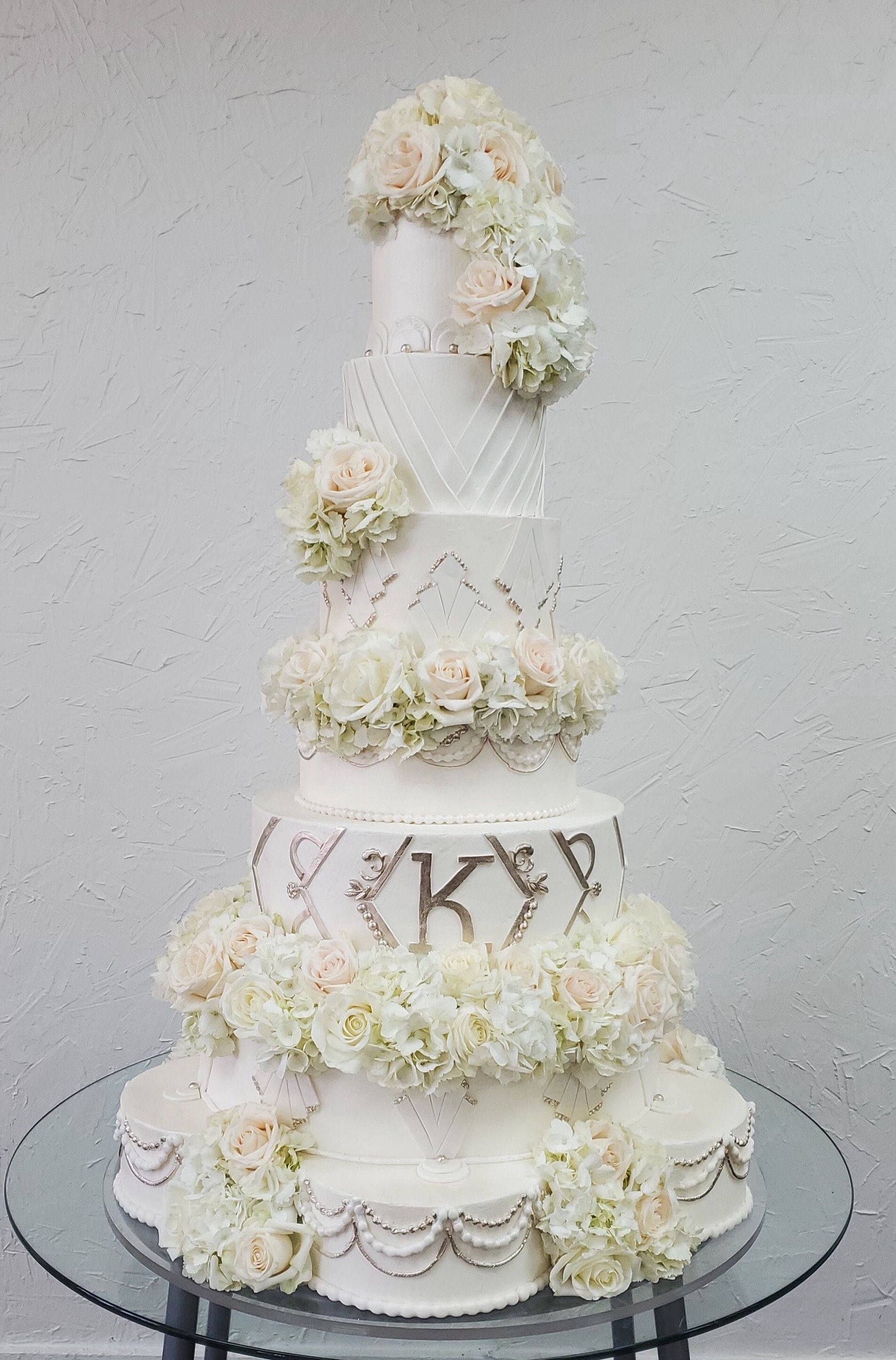 a wedding cake with flowers on it is sitting on a glass table .