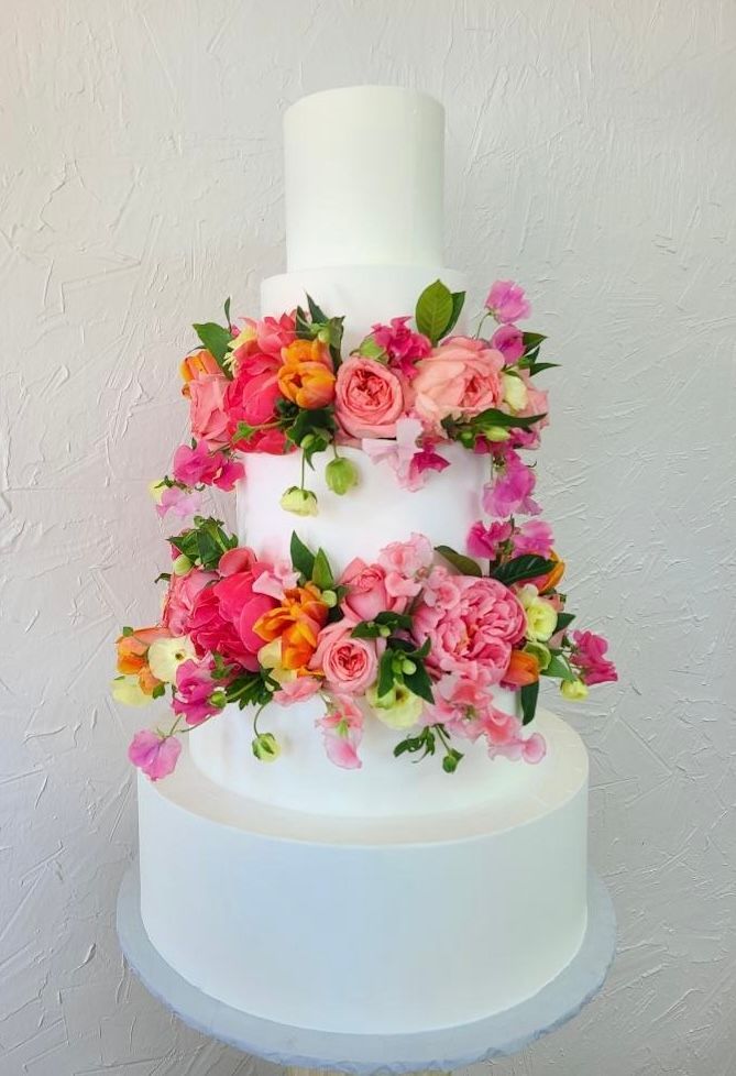 a white wedding cake with pink and orange flowers on it