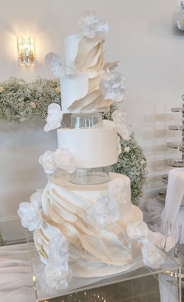 a white wedding cake is sitting on top of a glass table .