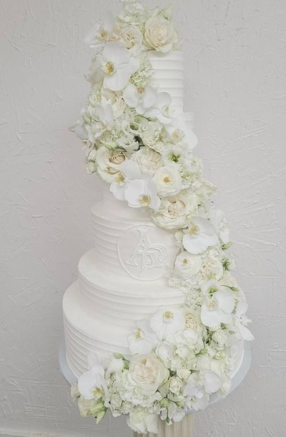 a white wedding cake with white flowers on it is sitting on a table .