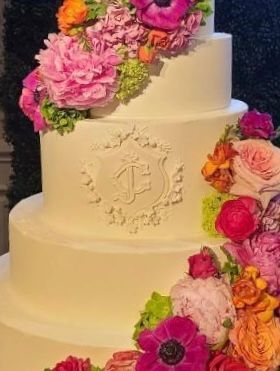 a white wedding cake with pink and orange flowers on it .