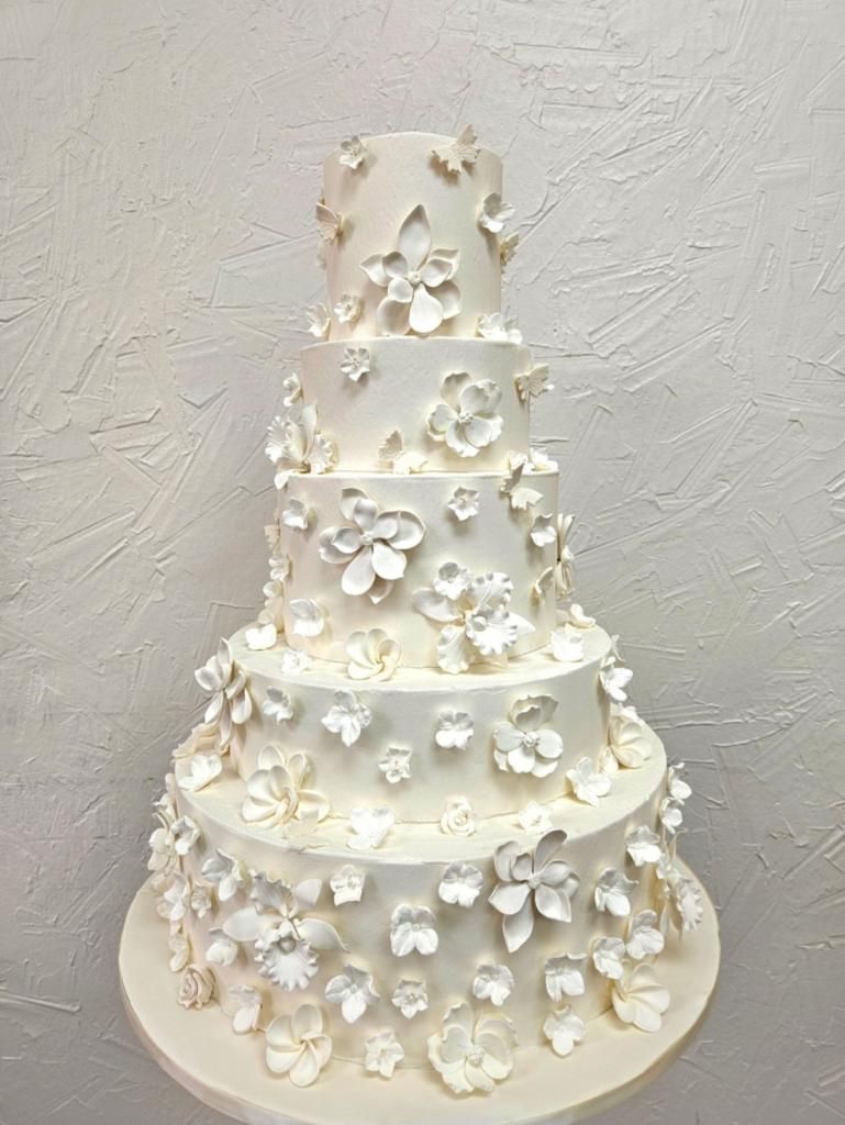 a white wedding cake with white flowers and butterflies on it .