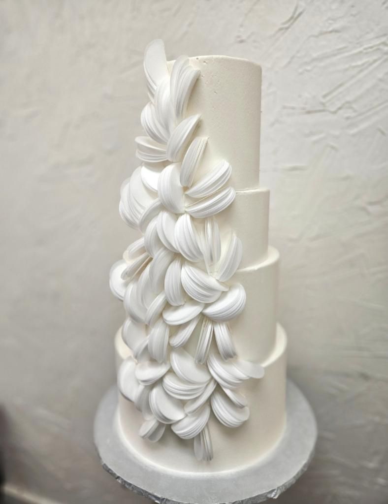 a white wedding cake with white flowers on it is sitting on top of a cake stand .