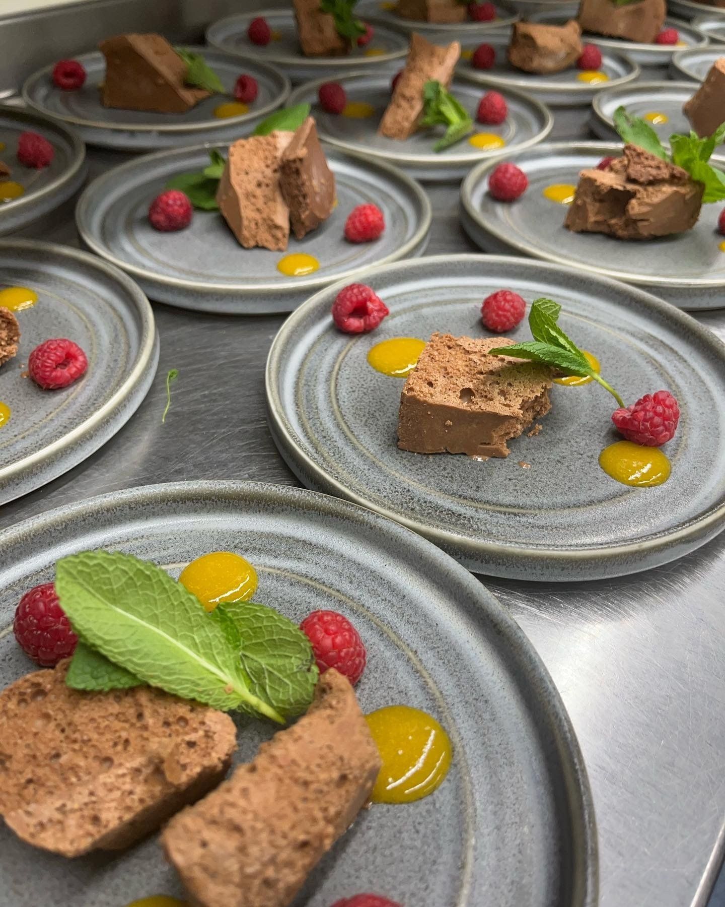 A bunch of plates of food with raspberries and mint on them