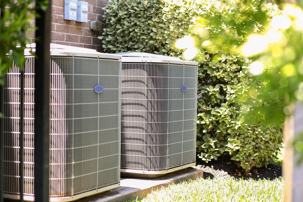Two air conditioners are sitting outside of a brick building.