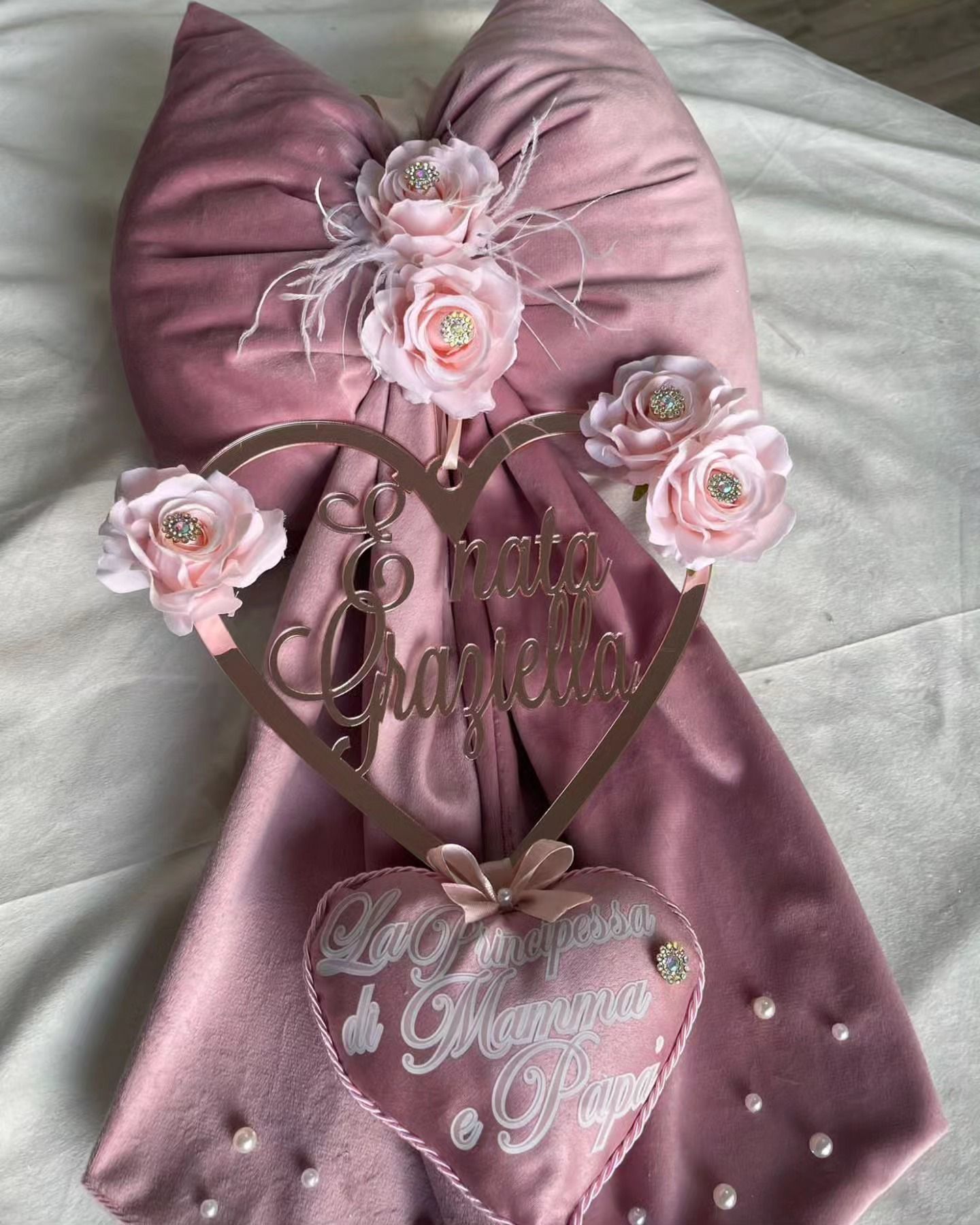 Un cuscino rosa con un cuore e dei fiori sopra