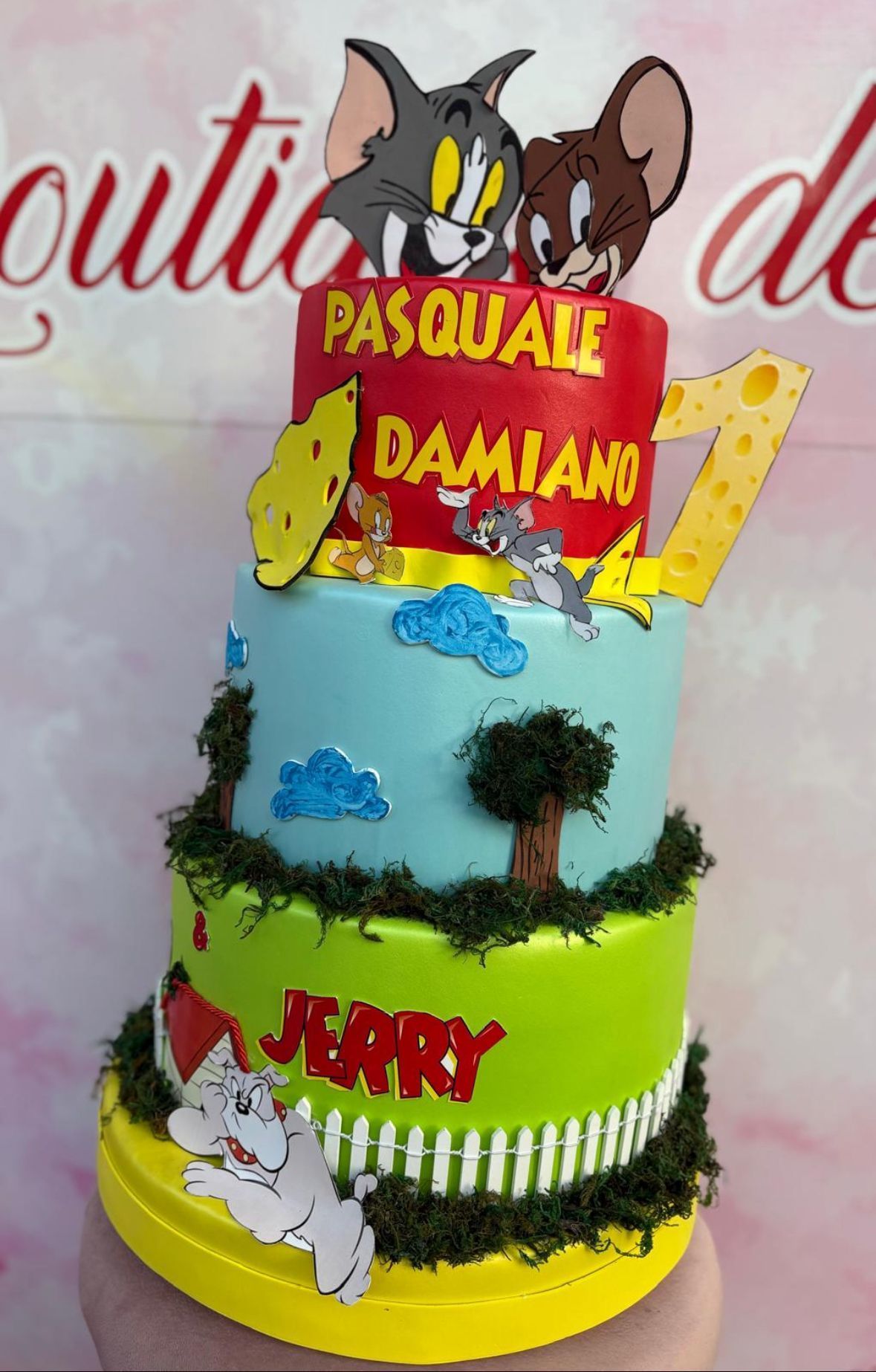 Una persona tiene in mano una torta con sopra Tom e Jerry.