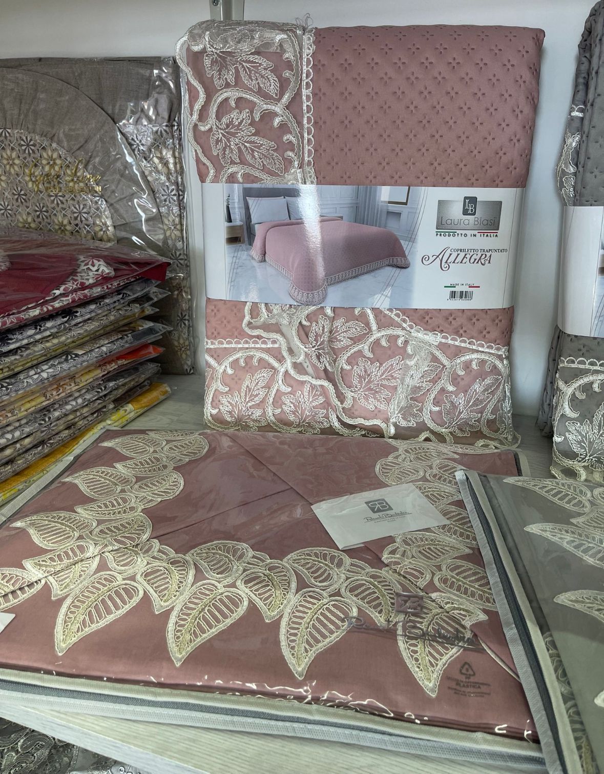 Un copriletto è appoggiato su un tavolo accanto a una pila di lenzuola.