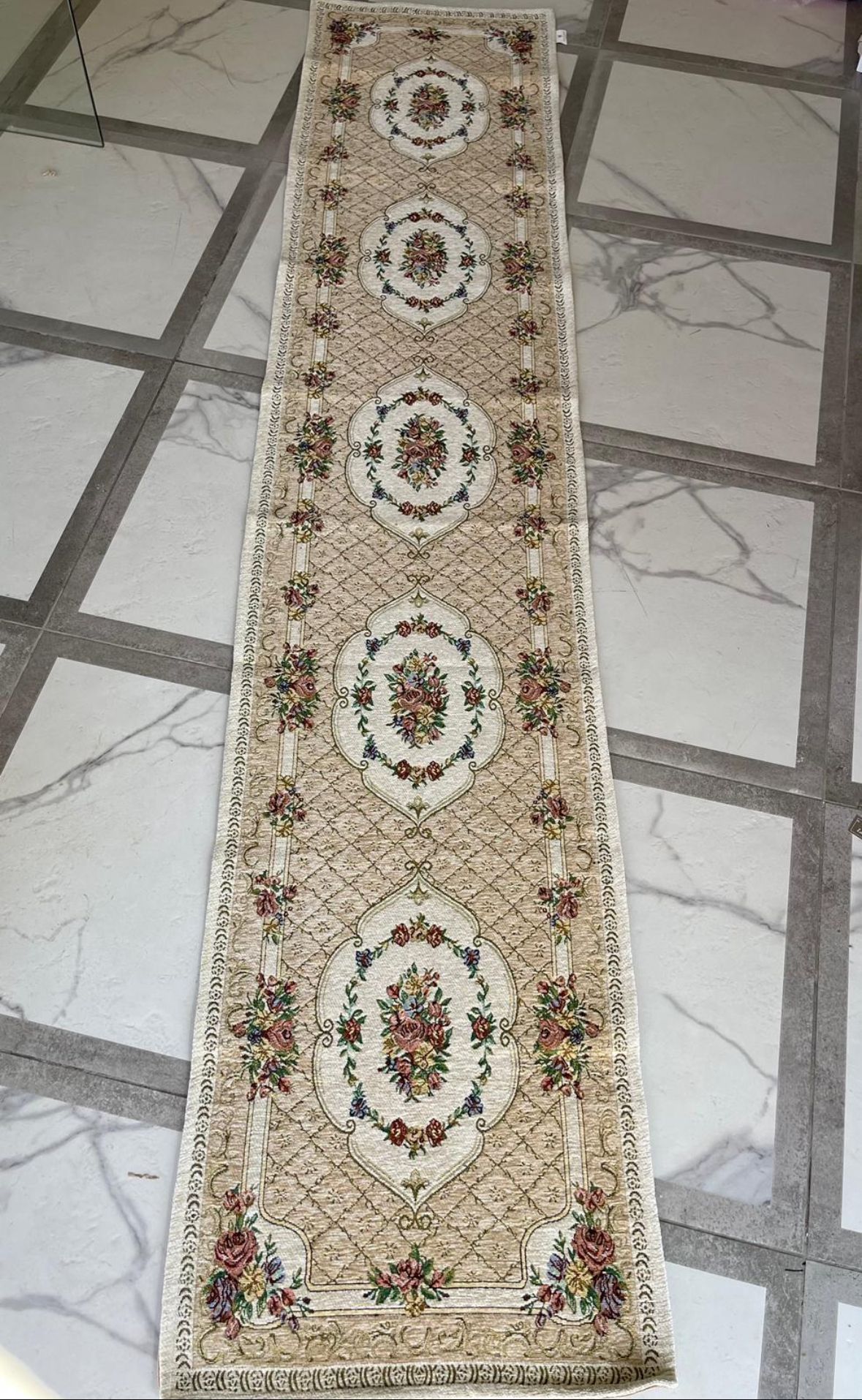 Un lungo tappeto è steso su un pavimento piastrellato.