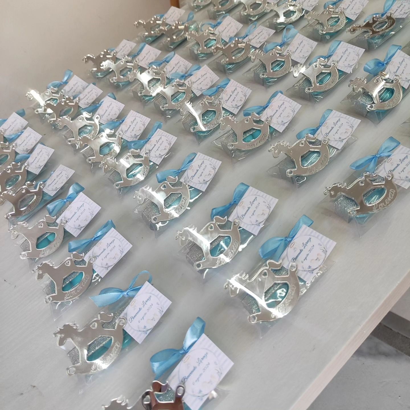 Una fila di decorazioni argentate con nastri blu sono allineate su un tavolo