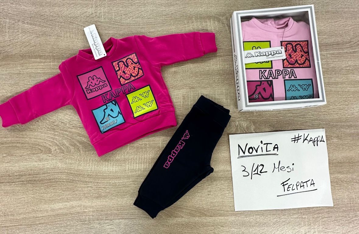 Un maglione rosa e pantaloni neri sono appoggiati su un tavolo di legno.
