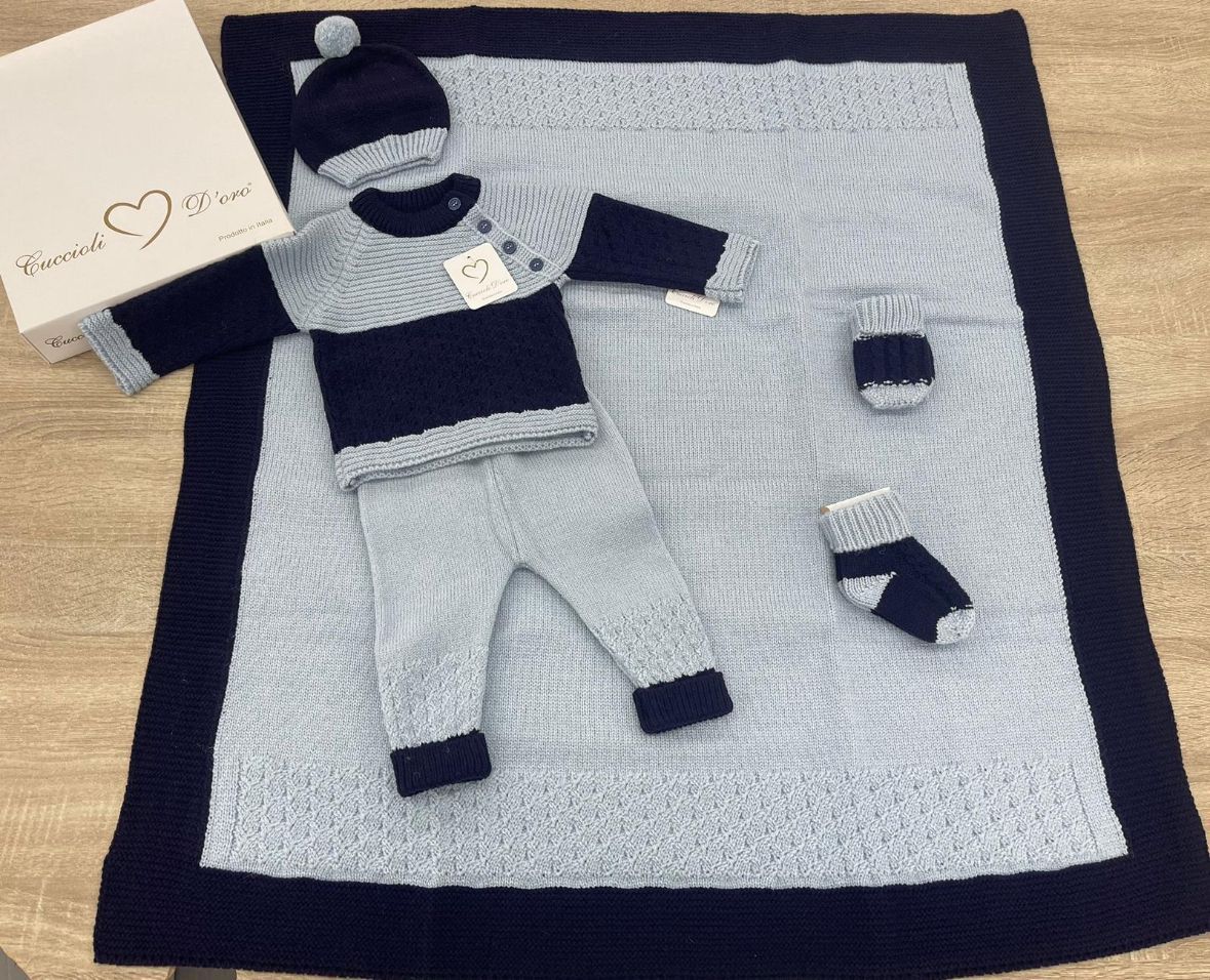 Un vestito lavorato a maglia per neonati è adagiato su una coperta